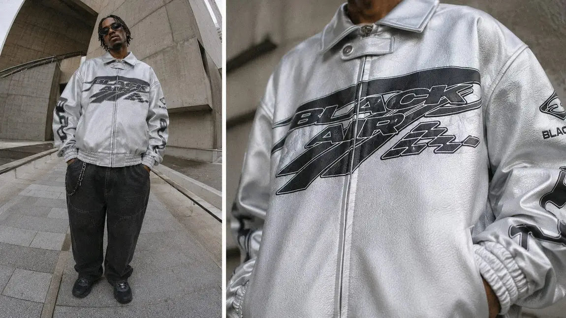 Silver racing-graphic streetwear jacket worn with black baggy jeans against concrete architecture