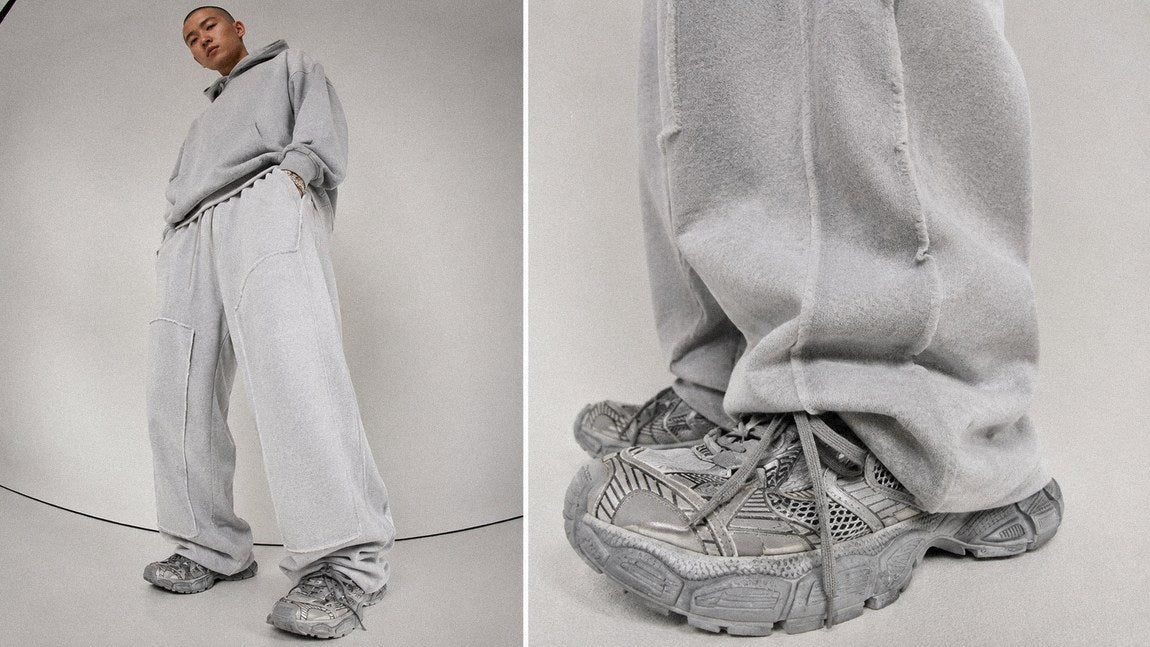 Oversized grey streetwear sweatpants and hoodie set on a plain studio background