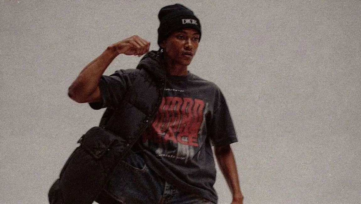 A beanie and shoulder bag are paired with a faded Streetwear t-shirt featuring a bold red design.