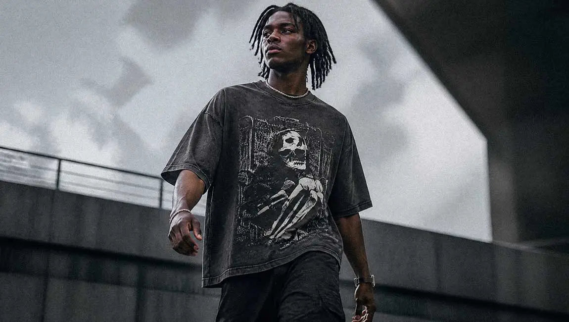 The model walks through a brutalist location wearing a dark Streetwear t-shirt with a skeleton print.