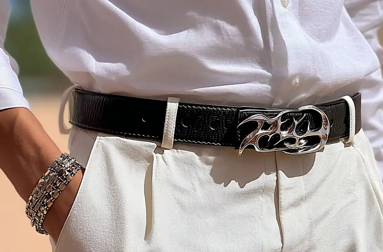 Black streetwear belt with a chrome flame buckle styled with white trousers.